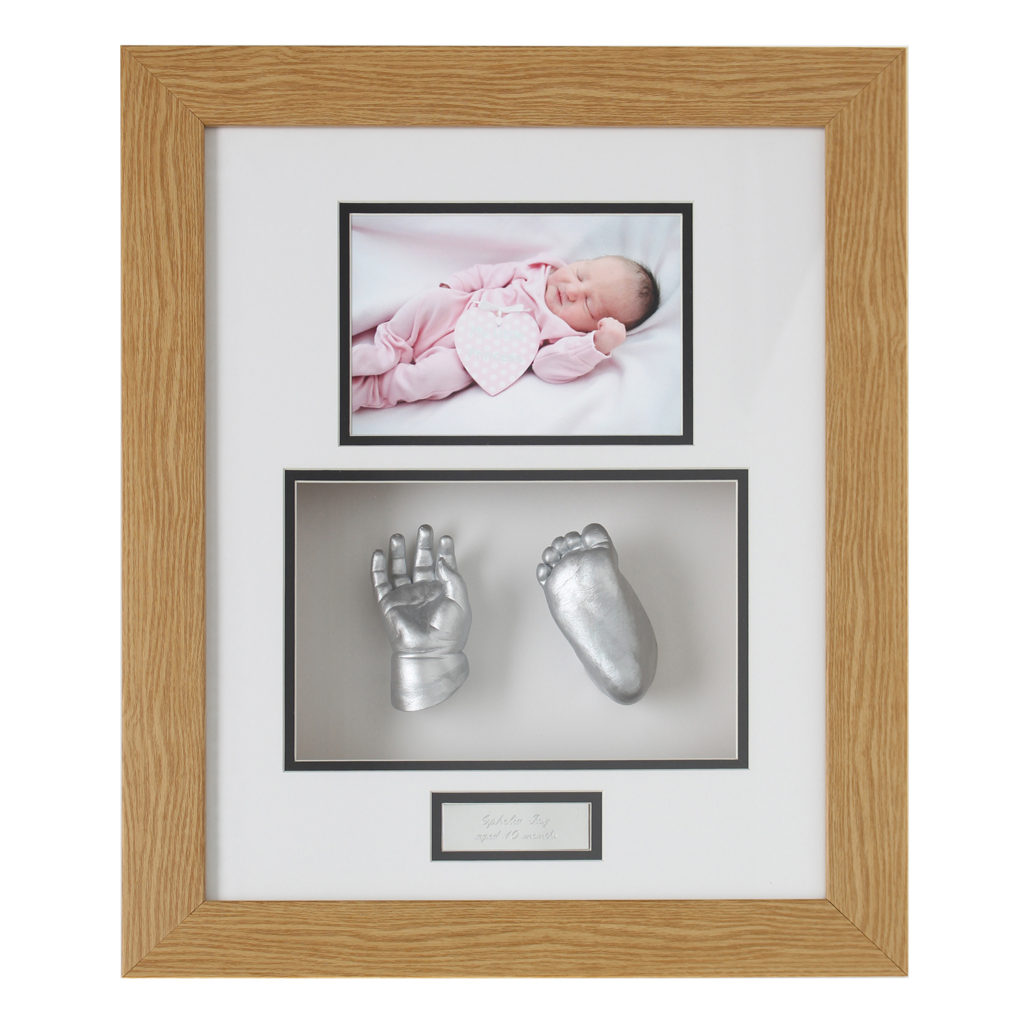 Silver baby hand and foot cast in a wood frame