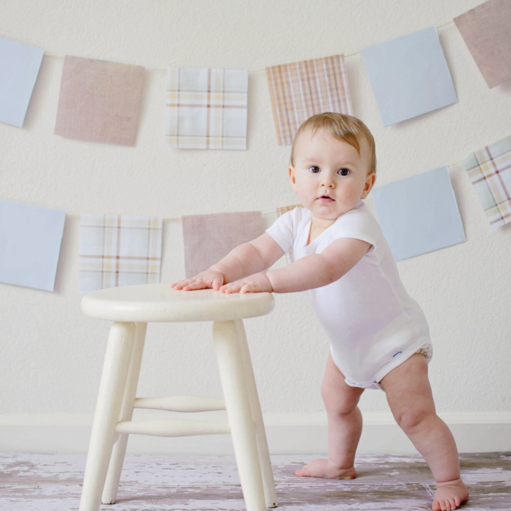 Baby leaning on a foot stool to stand