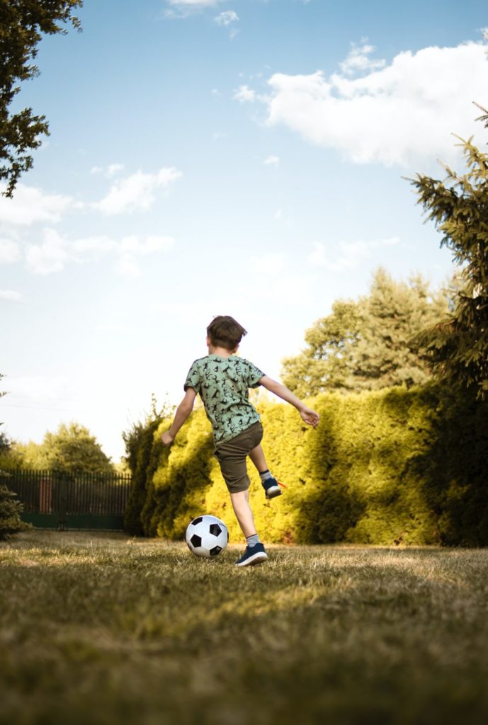 a young boy plays football in his back garden