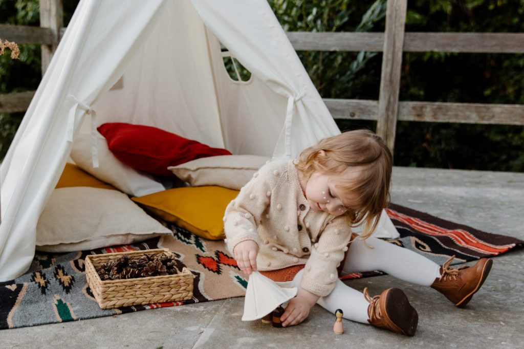 a small girl playing outside with her den