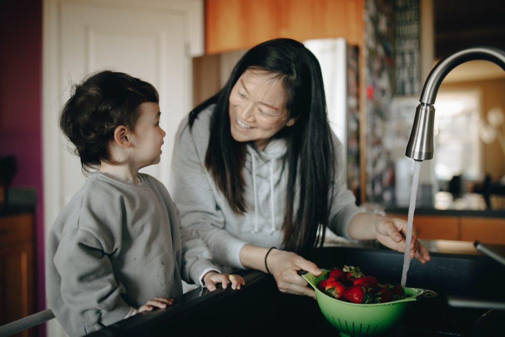 child helping his mother wash strawberries